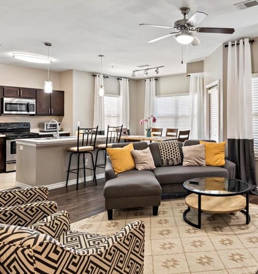 a living room with a couch coffee table and a kitchen in the background