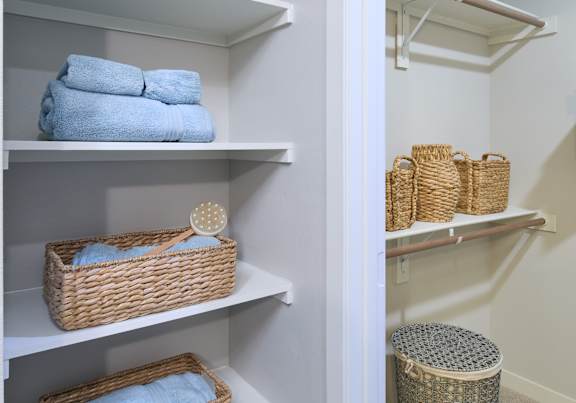 A white closet with baskets and towels.