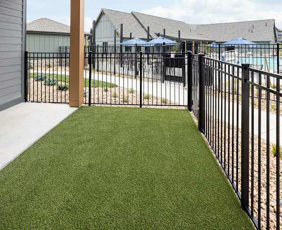 A balcony with a black railing and a green lawn.