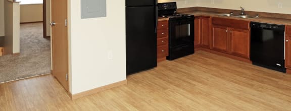 a kitchen with black appliances and wood flooring