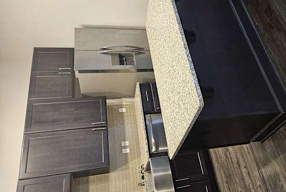 A kitchen with black cabinets and a stainless steel stove top.