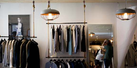 A woman is shopping in a clothing store with a variety of shirts hanging on the racks.