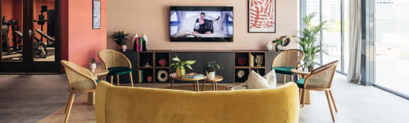 a living room with a yellow couch and chairs and a television