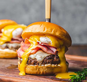 a cheeseburger on a wooden cutting board with other cheeseburgers in the background