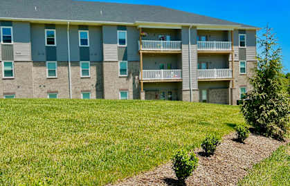 an apartment building with green grass and bushes in front of it