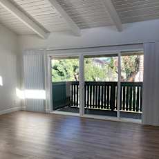 A room with wooden floors and a sliding glass door leading to a balcony.