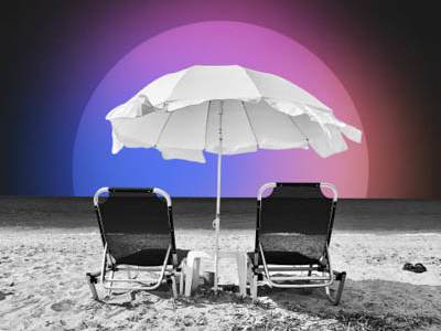 Two chairs are positioned under a white umbrella on a sandy beach.