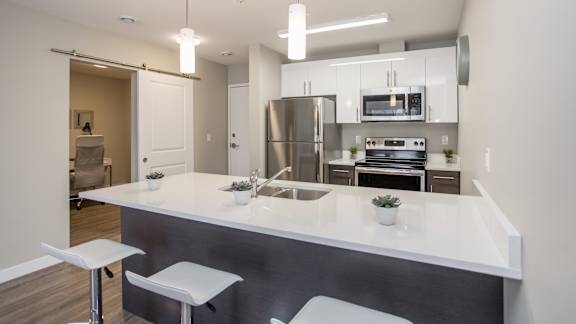 A modern kitchen with a white countertop and stainless steel appliances.