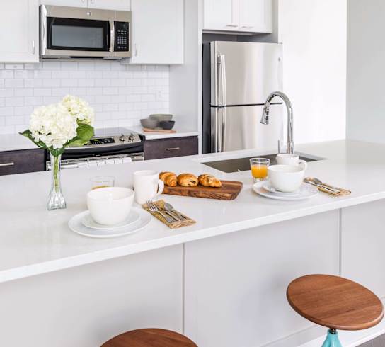 A kitchen with white cabinets and a white countertop with breakfast items on it. at The Pennsylvanian Apartments, Pittsburgh, Pennsylvania