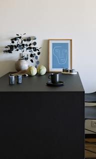 a dining room with a black table and two chairs and a lamp on the wall