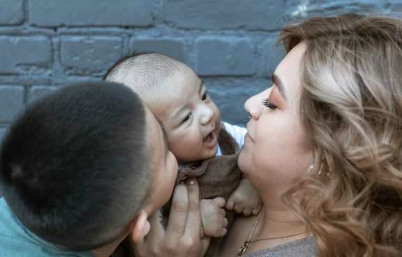  A young child is being held by an adult and another child.