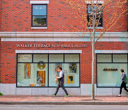 A red brick building with a sign that says Walker Terrace Sidewalk Gallery.