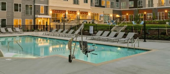 an apartment building with a swimming pool at dusk at Metropolis Apartments in Glen Allen, VA 23060