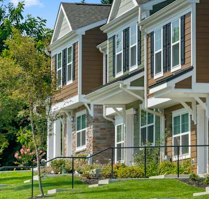 Sunny day at Carrolltown Village.  Shot of the exterior of the building highlighting the whimsical colors popping against a fresh white trim and lush landscaping.  Handrails on select walk ways.