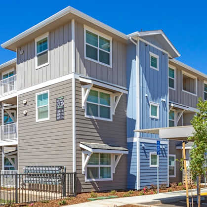 A modern apartment complex with a parking area in front.