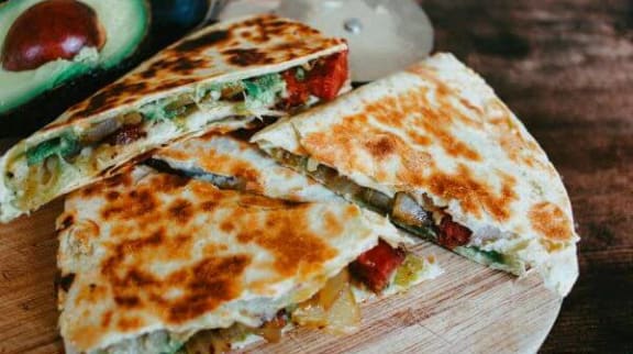 a cut in half quesadilla on a wooden cutting board