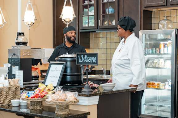 a man and a woman standing behind a counter in a cafe