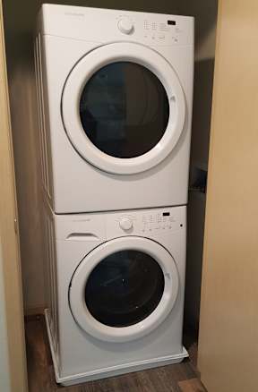 A white front loading washing machine is stacked on top of another white front loading washing machine.