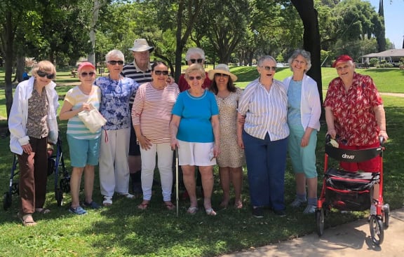 a group of seniors standing under a tree in a park