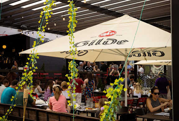 A group of people are sitting at tables under umbrellas with the word "Billie" on them.