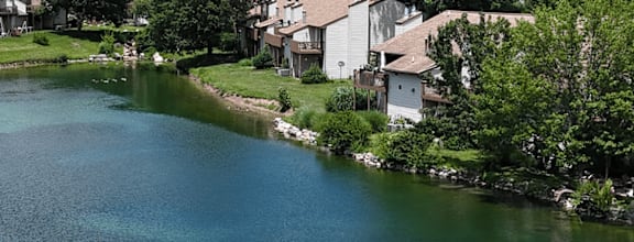 A lake surrounded by houses and trees under a blue sky.