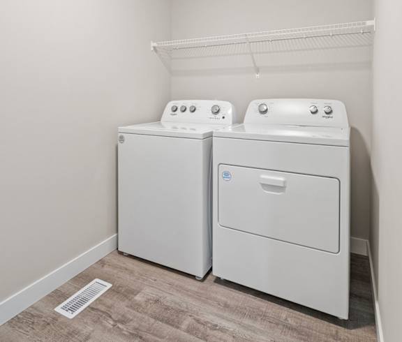 a washer and dryer in a room with a wood floor and white walls
