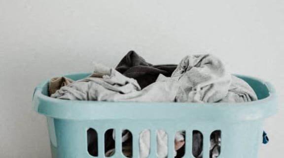 a laundry basket full of clothes on a white