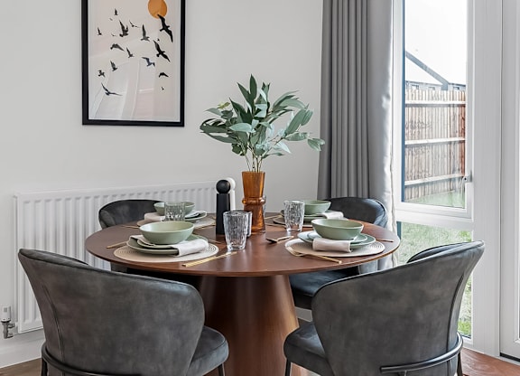 A dining room with a table set for two and a potted plant on the table at The Woodlands Apartments, Milton Keynes, MK5 6GS