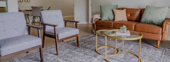 A living room with a grey couch, a coffee table, and a large tapestry hanging on the wall.