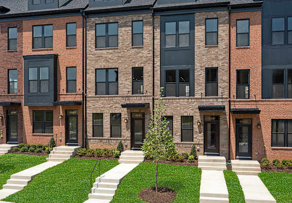 Woods at Brambleton Town Center exterior shot.  Showcasing five homes built row home style with lush landscaping and ample parking.
