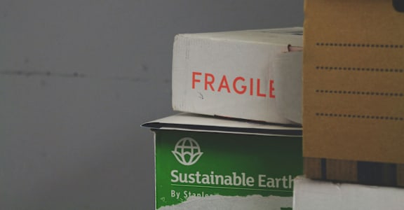 A cardboard box with the word "FRAGILE" written on it is stacked on top of another box.