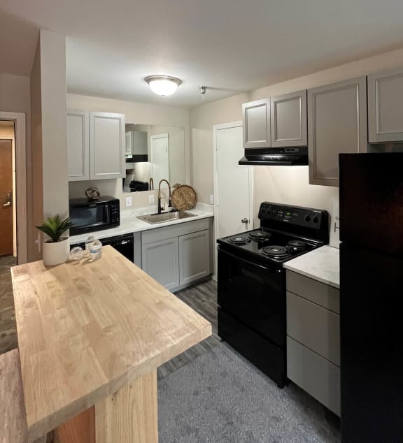 a kitchen with white cabinets and black appliancesat The Lodge Apartments, Tulsa, 74129