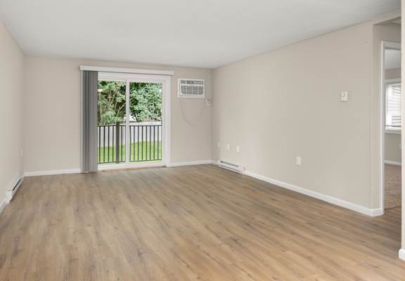 an empty living room with a sliding glass door to a balcony