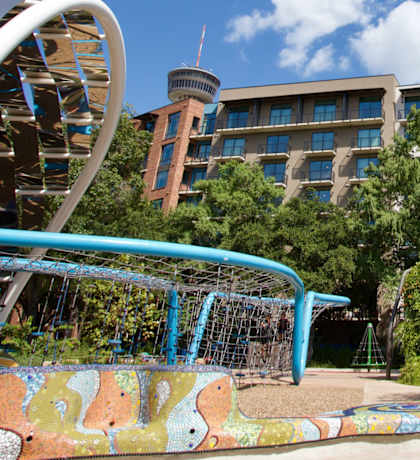 A playground with a slide and a building in the background.
