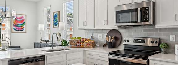 A modern kitchen with a white countertop and stainless steel appliances.
