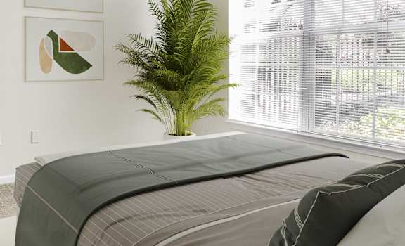 A bedroom with a bed, a plant, and two framed pictures on the wall.