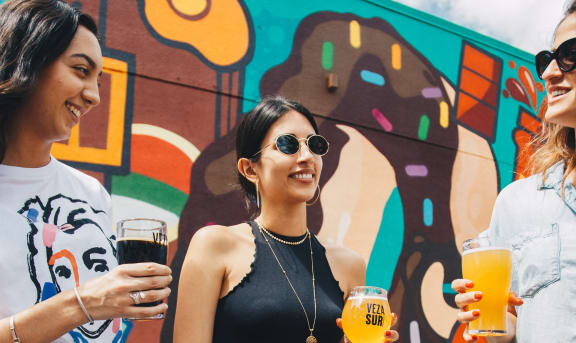 3 women standing and holding beers