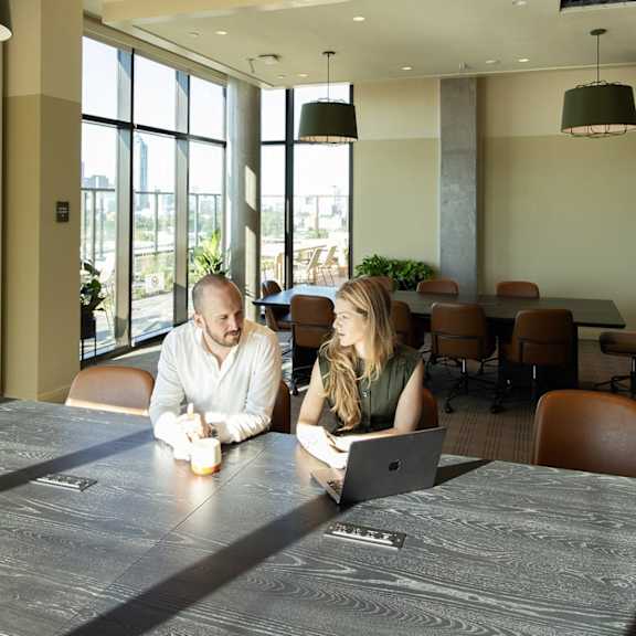 Two people sitting at a table with a laptop. at Scout Living, powered by Placemakr Apartments, Atlanta, GA, 30308