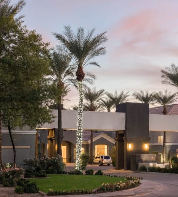The Highland Apartments front entrance with lit palm trees and grass