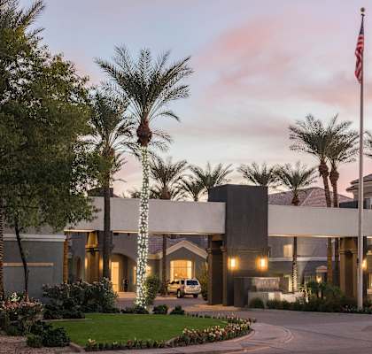 The Highland Apartments front entrance with lit palm trees and grass