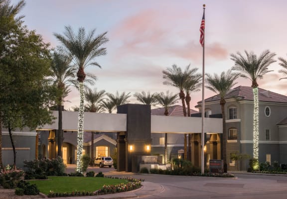 The Highland Apartments front entrance with lit palm trees and grass