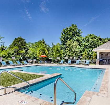 A large outdoor swimming pool surrounded by lounge chairs and umbrellas.