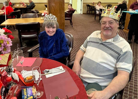 A man and a woman wearing paper crowns at River Commons Senior Living, California