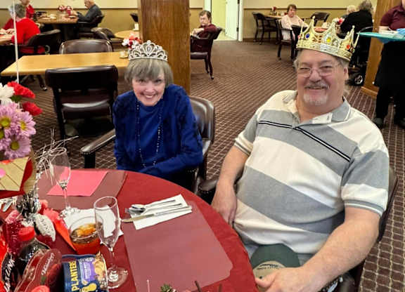 A man and a woman wearing paper crowns at River Commons Senior Living, California