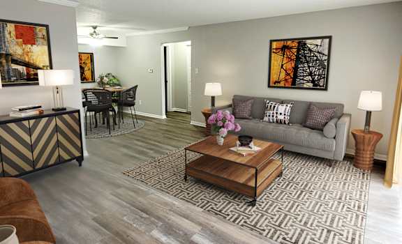 a living room with a couch coffee table and a dining room table in the background