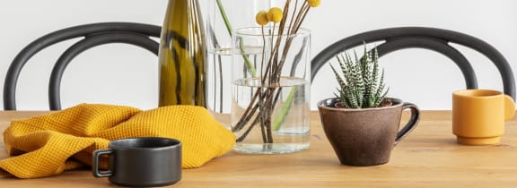 flowers in a vase and cups on a table in a kitchen stock photo #