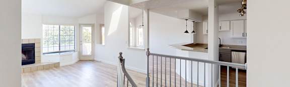 A spacious room with a skylight and a staircase with a metal railing.