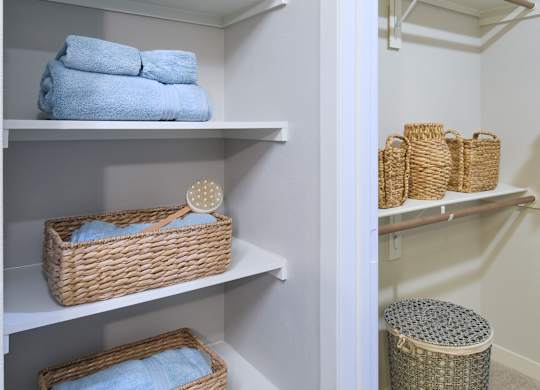 A white closet with baskets and towels.