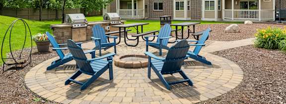 an outdoor patio with blue chairs and a fire pit at Cityscape, St Louis Park, 55416
