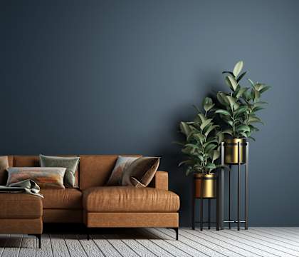 a sofa with brown cushions in a living room with a dark blue wall